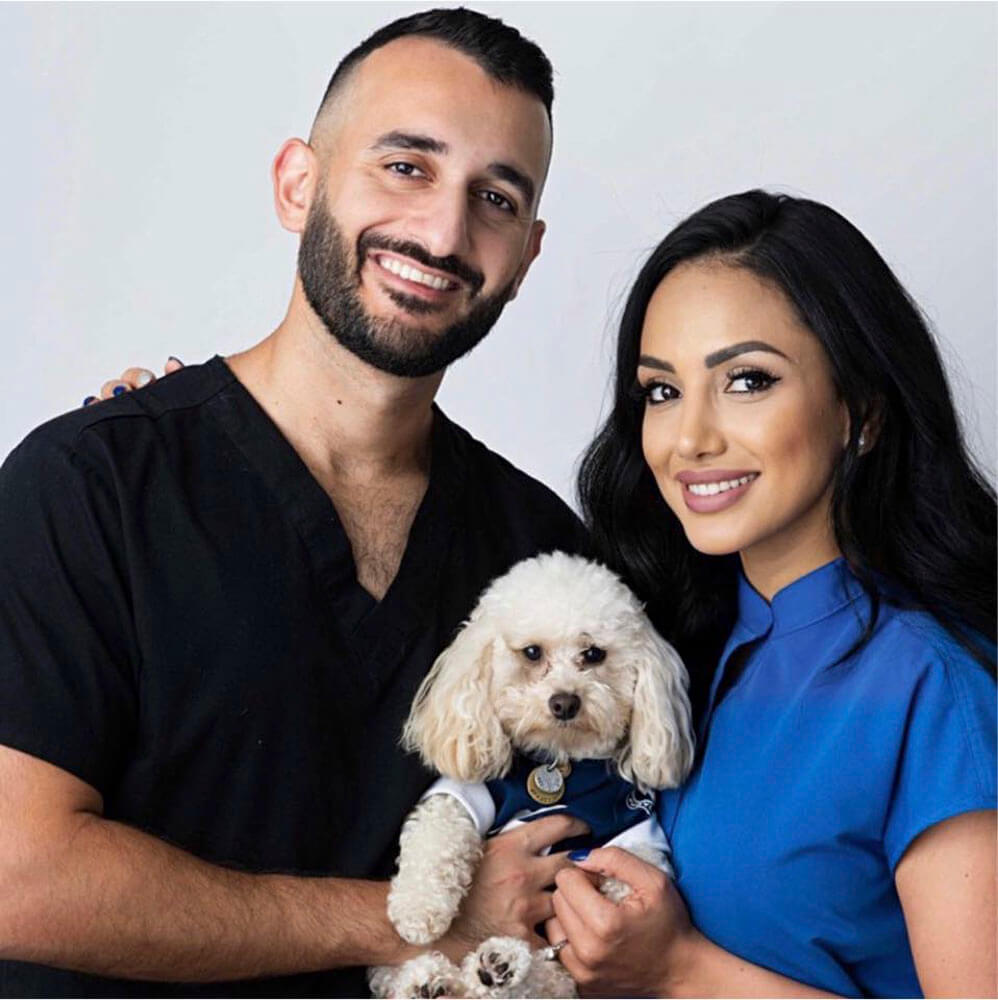 Dr. Paradis Esi of ESI Dentistry - Esthetic Smiles & Implants next to wife and holding a small dog in a shirt